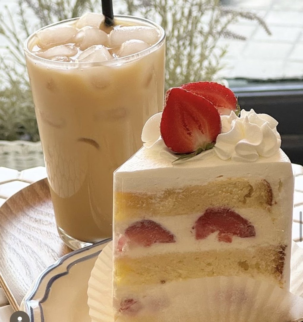 Part de fraisier servie avec un café glacé